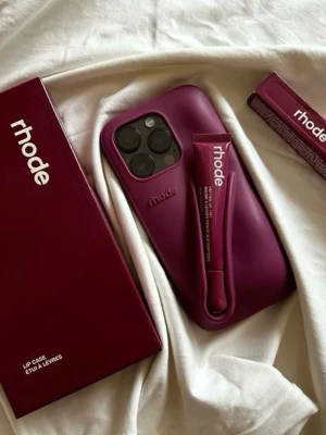 iPhone 15 pro Rhode raspberry case with lip treatment  - Snyggt vinrött mobilskal från rhode i mjukt silikonmaterial. Skalet har en unik hållare för läppbalsam på baksidan och passar perfekt för dig som vill ha både stil och funktion. Märket rhode är tydligt präglat på skalet. Perfekt accessoar till mobilen!