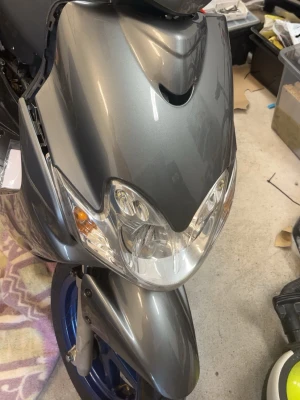 kåpa till scooter - Säljer en grå metallic framskärm och kåpa till scooter eller moped. Kåpan har integrerade klara strålkastare och en sportig design med mjuka linjer. Passar dig som vill byta ut eller uppgradera fronten på din scooter. Sidan på vingen är färgen lite borta. Kolla bild 4