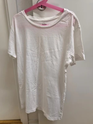 Vit basic t-shirt från 157 XS - Klassisk vit t-shirt från 157 i 100% ekologisk bomull. Modellen har rund halsringning och korta ärmar, perfekt för en clean och enkel stil. Passformen är normal och tyget känns mjukt mot huden. Finns en gul fläck.