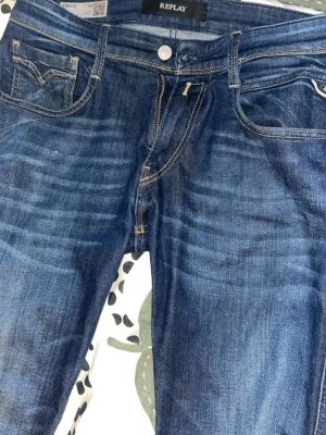 Mörkblå Replay jeans  - Snygga mörkblå jeans från Replay, passform och klassiska fem fickor. Jeansen har slitningar och kontrastsömmar som ger en cool look. Tillverkade i denim med stretch för extra komfort. Perfekta för dig som gillar en trendig och avslappnad stil.