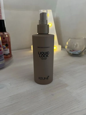 Keune Liquid Lock hårspray 200ml - Beige sprayflaska med Keune Liquid Lock, en hårspray för styling. Flaskan rymmer 200 ml och har en praktisk pump. Perfekt för att fixera frisyrer och ge stadga utan att tynga ner håret. Aldrig använd. Nypris 349.