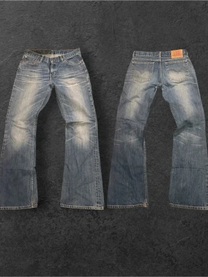 Extremt feta 529 från Levi's I bootcut  - Säljer ett par klassiska blå bootcut jeans från Levi's med slitna detaljer och ljusa partier framtill och baktill. Jeansen har fem fickor, knappgylf och en skön passform som ger en avslappnad look. Perfekta för dig som gillar vintage vibe. Passar mig i 185 70kg, mått 40 midja, 103 längd, benöppning 23