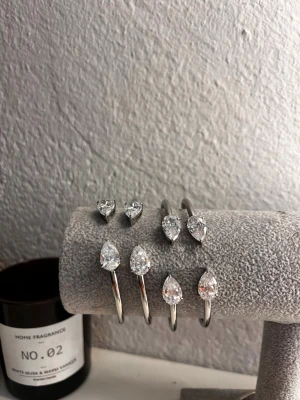 Silverfärgat armband med droppformade stenar - När man köper så köper man ett!         Stilrent armband i silverfärgad metall med två stora, droppformade klara stenar i varje ände. Enkel och modern design som ger en lyxig känsla. Perfekt accessoar för att lyfta din outfit med lite extra bling.