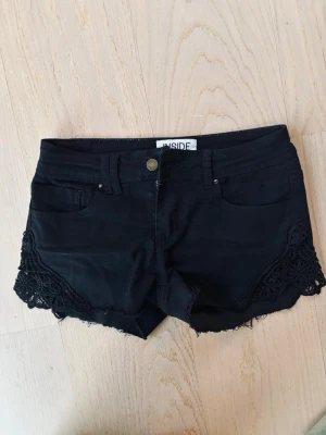 Svarta lowwaist jeansshorts med spetsdetaljer - Jättesnygga svarta jeansshorts från inside (köpta i Spanien) med spetsdetaljer på sidorna och backfickan. Pris kan diskuteras 