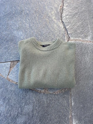  stickad tröja - Snygg olivgrön stickad tröja  med rund halsringning och ribbade muddar. Tröjan har en enkel, clean design och är tillverkad i mjukt material som passar perfekt till lager på lager. Långärmad modell.