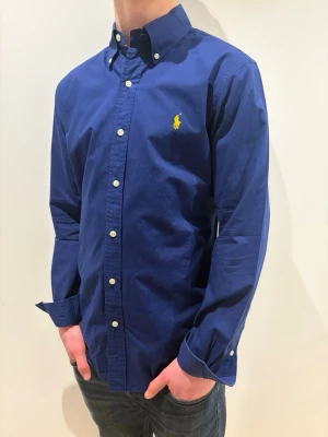 Ralph Lauren - Tja säljer en Ralph Lauren skjorta i färgen blå och storlek s passar 170-180 cm ungefär nypris 1595kr mitt pris 299kr. Inga defekter som hål eller fläckar. Skriv vid fråga eller fundering. 