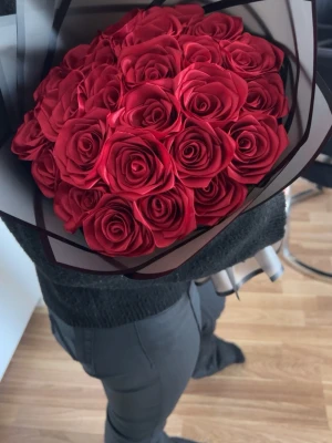 Bukett med röda konstrosor - Snygg bukett med röda konstgjorda rosor inslagna i svart och transparent cellofan med en röd rosett. Perfekt som present eller dekoration. Rosorna har realistiskt utseende och buketten är elegant inslagen.