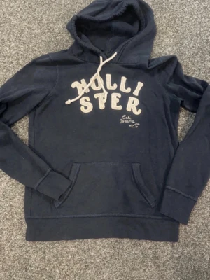 Hollister hoodie vintage - Vintage Hollister hoodie i fint skick och inget att klaga på! Inga defekter! Det står L på etiketten men den sitter som en S! Skriv till mig vid eventuella frågor jag svarar snabbt!