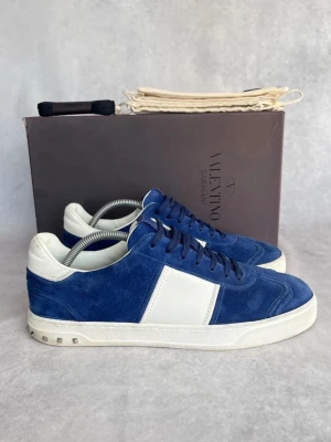 Valentino Flycrews - Snygga sneakers från Valentino i blå mocka med vita detaljer och vit sula. Skorna har klassisk låg profil, blå skosnören och små nitar på hälen. Perfekta för dig som vill ha en stilren och exklusiv look, storlek 43