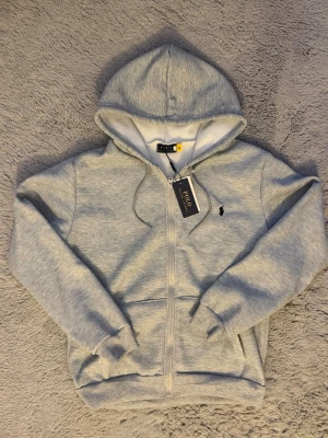 Ljusgrå hoodie Polo Ralph Lauren - Säljer min Polo Ralph Lauren-hoodie i ljusgrått med taggar kvar.  ⭐️ Skick: Oanvänd / Ny 📦 Frakt: Inom 24 timmar 