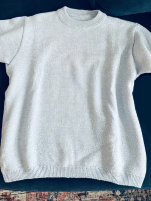 Ljusblå stickad t-shirt - Säljer en stilren ljusblå stickad t-shirt. Tröjan har en mjuk och tjock stickning. Perfekt för dig som gillar minimalistisk och enkel stil. Från Gina Young men jag har klippt av lapparna. Den är inte nopprig. 