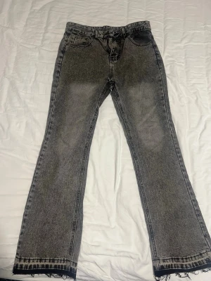  Cali jeans i ljusblå och svart tvätt  - Två par Cali jeans, ett par i ljusblå tvätt och ett par i svartgrå tvätt. Båda har slitna detaljer vid benslut och lätt utsvängda ben Storlek 30/32.        1 för 450, 2 för 700