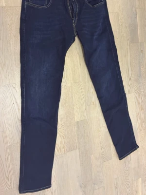 Mörkblå slim fit jeans - Snygga mörkblå slim fit jeans med kontrastsömmar och klassiska fem fickor. Bakfickorna har dekorativa sömmar. Perfekta för en trendig och avslappnad stil. Materialet känns mjukt och stretchigt för extra komfort.