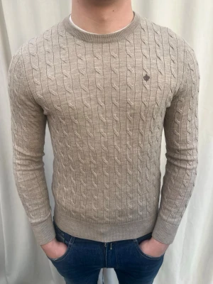 Beige kabelstickad tröja Morris  - Sjukt snygg kabelstickad tröja från Morris.100% merinoull. Nyskick. Strl M, personen på bilden är 184 cm lång. Skicka gärna prisförslag. Kika in min profil för mer schyssta plagg 