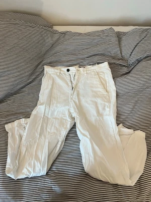 Vita linnebyxor från HM - Snygga vita linnebyxor från H&M i relaxed fit-modell i storlek 30. Byxorna har klassiska sidfickor, bälteshällor och stängs med knapp och dragkedja. Perfekta att ha nu i sommar när det blir varmt.