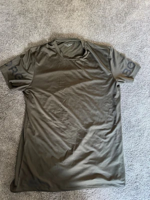 Olivgrön Björn Borg t-shirt M - Snygg olivgrön t-shirt från Björn Borg med diskret logga på ärmarna. Tillverkad i ett mjukt och lätt syntetmaterial som passar perfekt till träning. Klassisk rund halsringning och korta ärmar för en clean look.