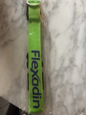Grönt halsband från Flexadin till hund  - Snyggt grönt halsband från Flexadin med justerbart spänne och plastdetaljer. Bältet har en enkel design med Flexadin-loggan tryckt i blått på framsidan. Oanvänd 