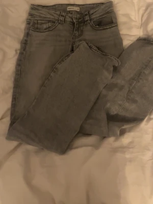 Gråa bootcut jeans från Gina Tricot - Snygga grå jeans från Gina Tricot med bootcut och klassisk femficksmodell. Jeansen har normal midja och är tillverkade i stretchigt denimtyg för en bekväm passform. Perfekta för en avslappnad och trendig look.