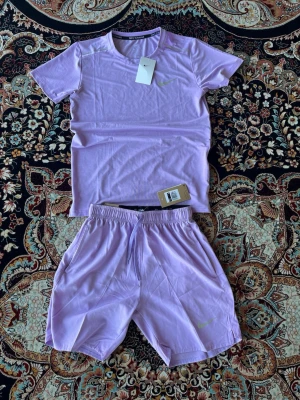 Nike Dress - Säljer ett stilrent träningsset från Nike i en snygg ljuslila färg. Setet består av en t-shirt och matchande shorts i lätt och bekvämt material som passar perfekt för både träning och vardag. Helt nytt med lappar kvar.
