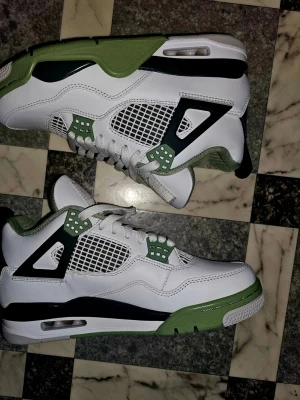 Air Jordan 4 Retro Seafoam  - Air Jordan 4 Retro Seafoam Oil Green. Klassisk meshpanel, gröna och svarta plastdetaljer samt synlig Air-sula. Ovandelen är i läder och mesh, yttersulan har gröna och vita partier med Jumpman-logga. Storlek 36.5. Helt nya och oanvända,  kommer med ersättningsbox. Unisex.