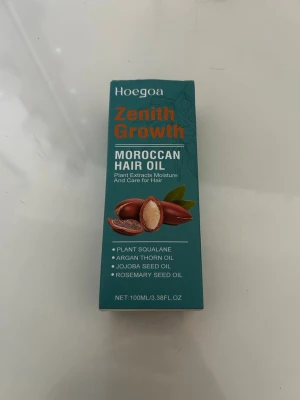 Hoegoa Zenith Growth Moroccan Hair Oil - Hoegoa Zenith Growth Moroccan Hair Oil med växtbaserade extrakt som squalane, arganolja, jojobaolja och rosmarinfröolja. Kommer i en brun plastflaska med svart lock och blå etikett. Innehåller 100 ml och ger fukt och vård till håret. Jag har använt lite av det men sedan har den bara legat oanvänt, se pil för hur mycket det är kvar..