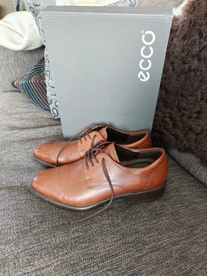 Bruna Kostymskor från ECCO - Som nya, använda 2 gånger på bröllop och begravning. Snygga bruna kostymskor från ECCO med klassisk design och smal tå. Tillverkade i mjukt läder med mörkbrun sula och diskreta sömmar för en clean finish. Hör av dig om du har frågor!