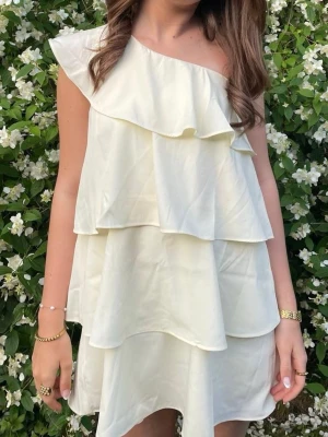 Vit omlottklänning med volanger - Söt vit kortklänning med flera lager volanger och oneshoulder-design, endast använd en gång!! 