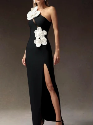 Svart långklänning  - Elegant svart långklänning med stora vita blommor. Klänningen har en hög slits framtill och figurnära passform. Köpt från Bella barnett för 983kr och säljer för 500kr då den är använd en kväll. 