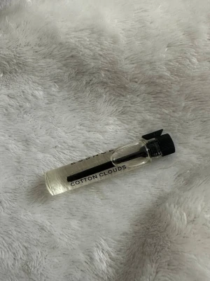 Parfymprov Cotton Clouds essnce - Litet parfymprov med doften Cotton Clouds. Flaskan är genomskinlig med svart skruvkork och text på sidan. Perfekt att ha med i väskan eller testa en ny doft.