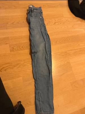 Ljusblå slim fit jeans - Säljer ett par ljusblå slim fit jeans med klassisk femficksdesign och normal midja. Jeansen har en enkel look utan slitningar eller dekorationer och är perfekta för en avslappnad stil. Materialet är troligtvis bomull med lite stretch för extra komfort.
