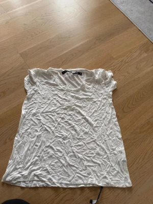 Vit t-shirt med v-ringning - En klassisk vit t-shirt med v-ringad hals och korta ärmar. T-shirten har en enkel och stilren design, perfekt att matcha med jeans eller shorts. Tillverkad i mjukt material för en bekväm känsla.