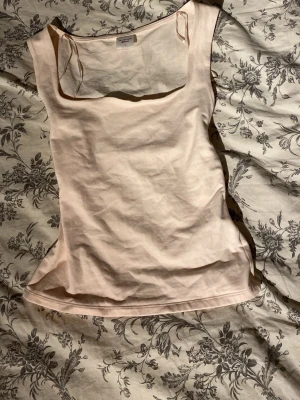 Ljusbeige linnetopp med fyrkantig ringning - Snygg ljusbeige linnetopp från gina med breda axelband och fyrkantig ringning. Perfekt att styla till jeans eller kjol för en clean look. Mjukt bomullsmaterial som känns skönt mot huden.