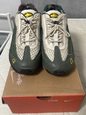 Nike Air Max 95 TT -  Air Max 95  sneakers med beige mesh och gröna läderdetaljer. Skorna har camo-mönstrad insida, gula loggor och svarta sulor. Snygg design med snabbsnörning och coola detaljer som sticker ut.