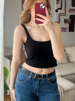 Svart croppad linnetopp från Nelly  - Trendig svart croppad linnetopp med breda axelband och rundad halsringning. Perfekt att matcha med höga jeans eller kjol för en avslappnad och snygg look. Enkel och stilren design utan mönster eller detaljer.