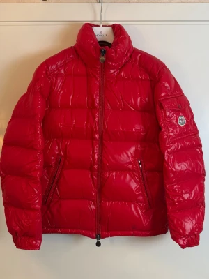 Moncler Maya röd  - Moncler Maya storlek 1. Skick 8.5/10 super fin men saknar Luva därav pris. 2990kr finns att köpa på våran hemsida, Fashionels.com