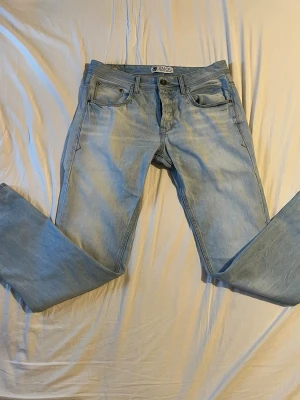 Ljusblå raka jeans från SMOG - Säljer ett par ljusblå jeans från SMOG med klassisk femficksdesign och raka ben i storlek 33, 32. Jeansen har en avslappnad passform och är tillverkade i denim med en snygg tvättad look. / Tveka inte på att höra av dig vid frågor! 👋