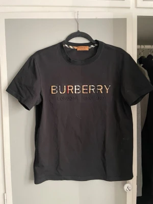 Svart Burberry t-shirt  - Snygg svart t-shirt från Burberry. Tillverkad i mjuk bomull och har Burberrys signaturmönster på insidan av kragen. Priset kan gå ner vid köp, hör av dig vid minsta lilla.