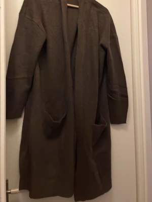Brun lång cardigan med fickor - Säljer denna långa bruna kostar från lager helt oanvänd i storlek xs bra nu till våren jätte fin 