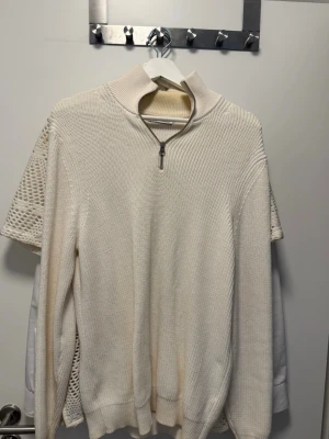 Vit stickad tröja med halv dragkedja Zara - Snygg vit stickad tröja från Zara med halv dragkedja och hög krage. Tröjan har ribbade muddar vid ärmslut och nederkant, samt en stilren och enkel design som passar till många outfits.