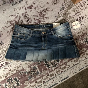Jeanskjol med plisserad kant - Plisserad jeanskjol i mörkblå tvätt med låg midja och klassiska jeansdetaljer. Märkt storlek 170 men motsvarar ungefär S. Kjolen verkar vara omgjord från jeans, vilket ger den en unik look. Perfekt för dig som gillar en y2k/DIY-inspirerad denimstil. Skriv gärna om du har frågor!