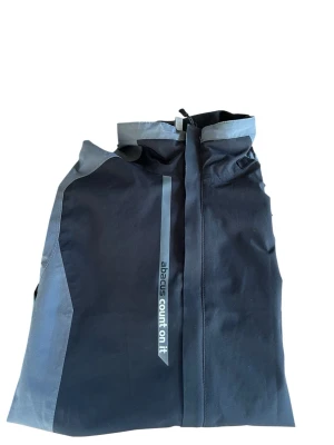 Abacus golf/regnjacka - Helt ny endast använd vid 1 tillfälle. Snygg grå svart  regnjacka från Abacus med ljusgrå detaljer och dragkedja framtill. Jackan har hög krage, tryckt logga på ärmen och reflekterande band med texten 'abacus count on it'. Perfekt för din golf runda. Kontakta mig vid frågor eller funderingar!