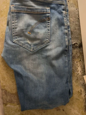 Ljusblå slitna jeans med raka ben - Ljusblå dondup george jeans w32. Jeansen har sköna fades o slitningar, inga defekter, bara att skriva om det är några funderingar 