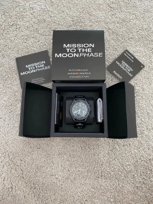 Omega x Swatch MoonSwatch  - Säljer en svart Omega x Swatch MoonSwatch Mission to the Moonphase. Klockan har biokeramiskt material, tachymeter och detaljerad urtavla med kronograf. Snygg och modern design med tydliga vita markeringar och svart textilband.