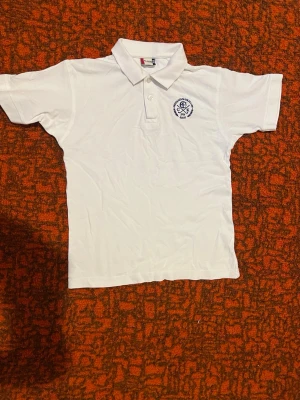 Vit pikétröja från Clique - Vit pikétröja från Clique med klassisk krage och knappar framtill. Tröjan har ett broderat märke på bröstet och är tillverkad i mjuk bomull. Perfekt för en clean och sportig stil.