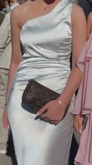 Blå oneshoulder långklänning - Ljusblå långklänning i oneshoulder-modell med slät, glansig yta (satin). Den är från six stories och köpt för ca 2500 kr förra året och är endast använd en gång på balen. I superfint skick förutom några små slitningar längst ned på baksidan (se bild). Den är i storlek 34 men passar mig som oftast har 36, jag är 170 och hade även klackar på bilderna.