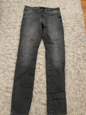 Grå slim fit jeans - Snygga grå slim fit jeans från Jack and Jones med klassisk femficksdesign och dragkedjegylf. Jeansen har en tvättad look och raka ben. Perfekta för en avslappnad och trendig stil. Jeansen är aldrig använda.