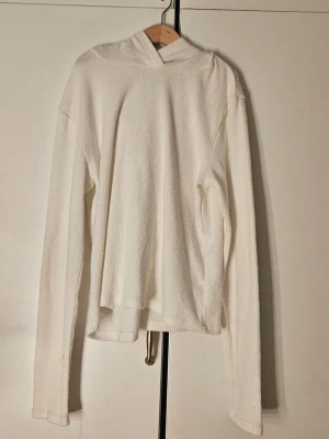 Vit stickad hoodie - Säljer en enkel och stilren vit hoodie i stickat material. Hoodien har en lös passform, lång ärm och en klassisk huva utan snören eller tryck. Den är bra för våren för att den är ganska tunn men ändå bra om man ba vill ha nåt över armarna