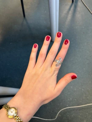 Silvrig spiralring i metall - Unik ring i silvrig metall med spiralformad design. Ringen består av flera tunna metalltrådar som är tvinnade i två snurror framtill, vilket ger ett coolt och modernt intryck. Perfekt för dig som gillar statement-smycken och vill sticka ut.