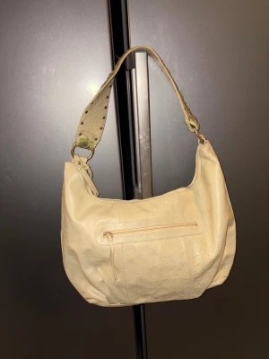 Boho väska i crocopräglat skinn - Axelväska i äkta skinn. Rymlig modell med dragkedjor och innerfickor . Mått 41*31 cm.  Broderad axelrem . Väskan är ny , har legat i kartong så det har blivit lite slitage på axelremmen om man tittar noga. 