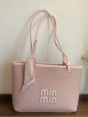 MIN MIN shoppingväska med scarf - Trendig shoppingväska från MIN MIN i två färger: ljusrosa och svart. Väskan har en stilren, rektangulär form med präglad logga framtill och långa axelband. Materialet är strukturerat och väskan pryds av en snygg scarf knuten vid handtaget för extra detalj.